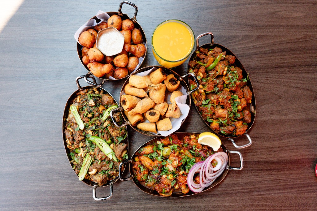 Indian catering spread of curries, snacks and mango lassi